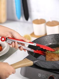 a person using a knife to cut meat in a skillet on a stove top