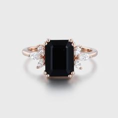 a black and white diamond ring with three diamonds on the band, set in rose gold