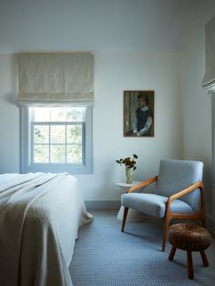 a bedroom with a bed, chair and painting on the wall next to a window