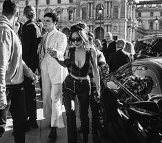 a woman walking next to a man in front of a car