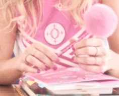 a girl holding a lollipop in her hand and looking at the book she is reading