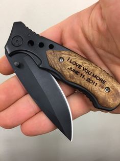 a person holding a knife with the words i love you more engraved on it's blade