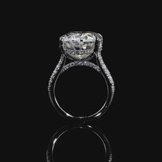 an engagement ring with a cushion cut diamond surrounded by pave diamonds on a black background