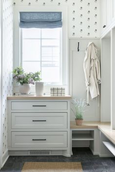 a kitchen with white cabinets, drawers and a potted plant in the window sill