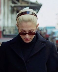 a woman in sunglasses is looking down at her cell phone