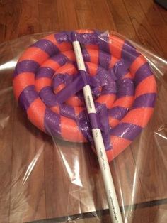 an orange and purple tube laying on top of a plastic bag next to a pencil