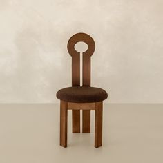 a wooden chair sitting on top of a white floor next to a wall with a circular design on the back of it