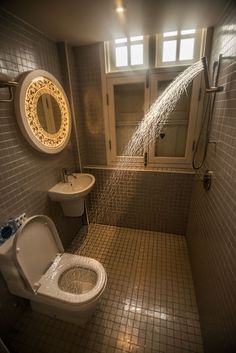 a bathroom with a toilet, sink and shower head mounted to the side of the wall