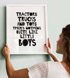 a woman holding up a framed poster with the words tractors and toys there's nothing quite like little boys