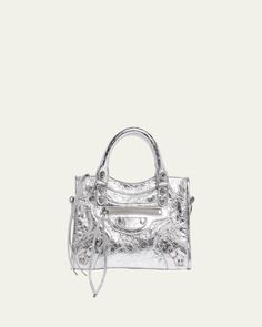 Balenciaga "Le City" top handle bag in metallic lamb leather     Rolled top handles     Detachable, adjustable shoulder/crossbody strap    Can be worn as a top handle or shoulder/crossbody bag     Zip top closure     Exterior, front zip pocket     Interior, one zip pocket     Approx. 6.3"H x 9.4"W x 2.5"D    Wipe clean    Made in Italy Silver Shoulder Bag With Top Handle And Detachable Handle, Luxury Metallic Bag With Adjustable Strap, High-end Silver Shoulder Bag With Silver-tone Hardware, High-end Silver Shoulder Bag With Detachable Strap, High-end Top Handle Shoulder Bag With Silver-tone Hardware, High-end Shoulder Bag With Silver-tone Hardware And Top Handle, High-end Shoulder Bag With Top Handle And Silver-tone Hardware, Luxury Metallic Shoulder Bag With Adjustable Strap, Silver Satchel With Adjustable Strap And Top Handle