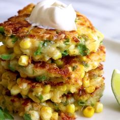 a stack of corn fritters with sour cream and garnish on top