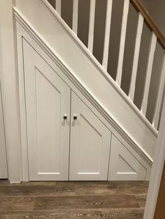 an under the stairs storage area with white cabinets and wood flooring in a home