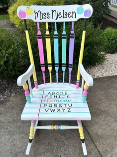 a colorful wooden rocking chair with writing on the back and arms that says, miss nelson