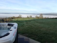 a hot tub sitting on top of a lush green field next to a large body of water