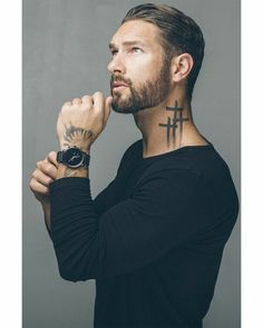 a man with a cross tattoo on his neck and hand in front of his face