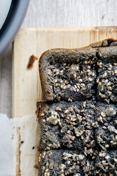 a piece of bread with seeds on it sitting on top of a wooden cutting board