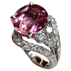 This cocktail ring has an asymmetric geometry that contrasts a beautiful pink Tourmaline on one side, with a vibrant and bright tone, oval cut ct 7.38 (from Nigeria) on the other side diamonds. The double shank structure is also completely set with brilliant-cut diamonds. The overall carat of the diamonds (color E/F clarity Vs) is 2.21ct. The name of this creation is HANAMI and takes its cue from the Japanese cherry blossom, which has bright pink petals. The stem design is meant to recall classic Japanese garden jumpers with their ticular curved lines. The whole ring is made of 18kt white gold Formal Pink Multi-stone Sapphire Ring, Luxury Pink Oval Diamond Ring, Dazzling Pink Oval Diamond Ring, Dazzling Oval Pink Ring, Modern Pink Diamond Rings, Pink Oval Diamond Ring With Dazzling Style, Dazzling Pink Oval Ring, Pink Oval Multi-stone Ruby Ring, Formal Oval Pink Sapphire Ring