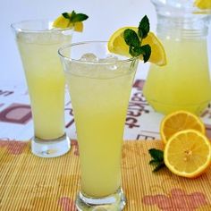 two glasses filled with lemonade sitting on top of a table