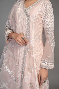 Light Pink Embroidered Anghrakha Style Pakistani Party Wear Frock embrace tradition in this gorgeous white ensemble with sequin and tilla motif details and delicate iconic flare. The angrakha is adorned with sequin sheets with thread outlines. Detailed Description: SKU: PB928 Detailing: Embroidery, Threads, Motifs, Dabka Color: Light Pink Fabric: Raw silk, Organza Design: Fully Embellished Dress with Embroidery Event: Party wear, Festive Off White Dress With Mirror Work For Diwali, Off White Wedding Dress With Mirror Work, Traditional Off-white Dress With Mirror Work, Bollywood Off White Dress With Mirror Work, White Semi-stitched Anarkali Set For Designer Wear, Traditional Off White Dress With Mirror Work, White Georgette Dress With Mirror Work, White Georgette Anarkali Set, White Semi-stitched Anarkali Set For Transitional Season