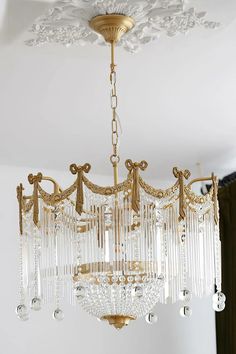 a chandelier hanging from the ceiling in a room with white walls and curtains