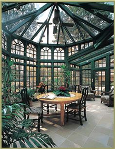 the inside of a green house with lots of windows and plants on the table in front of it