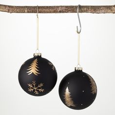 two black ornaments hanging from a tree branch with gold snowflakes on the top