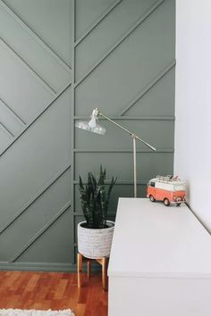 a living room with a couch, table and lamp on the wall next to a potted plant