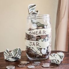 a jar filled with money sitting on top of a wooden table