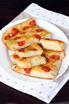 a white plate topped with cheesy bread covered in cheese and tomato toppings