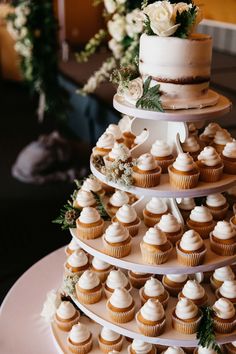 a three tiered cake with cupcakes on it