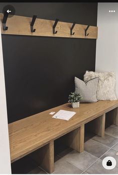 a wooden bench sitting next to a black wall with hooks on it's sides