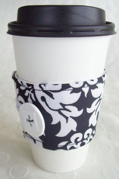 a coffee cup with a black and white flower design on the bottom is sitting on a table