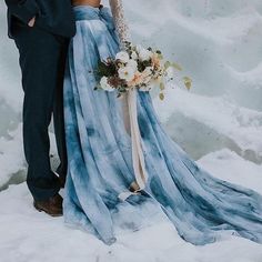 a bride and groom standing in the snow