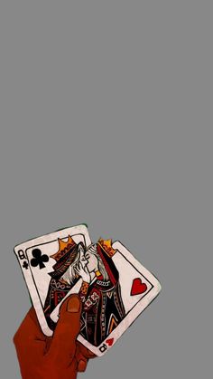 a hand holding two playing cards in front of a gray background with the king and queen of spades on it