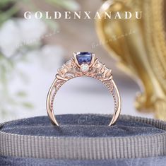 an engagement ring with a blue diamond in the center on top of a velvet box