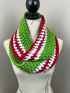 a green, red and white crocheted scarf on a mannequin