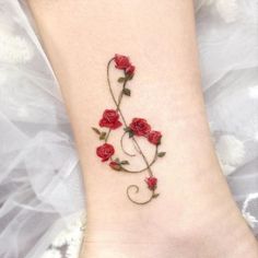 a woman's foot with red roses on it and a trellis tattoo design