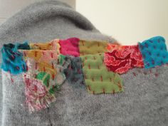 a close up of a person's sweater with different colored pieces of fabric on it