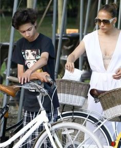 two people standing next to each other with bicycles in front of them and one person wearing sunglasses