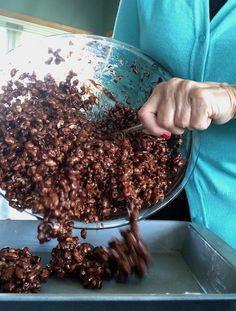 a woman is holding a bowl full of chocolate flakes with one hand on the side