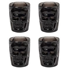 four black skull shot glasses sitting next to each other on a white background with the same design