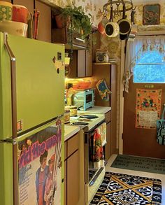 a green refrigerator freezer sitting inside of a kitchen next to a stove top oven