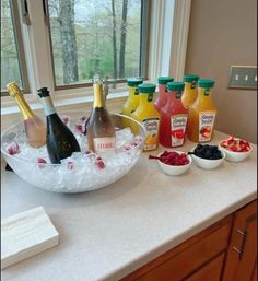 bottles of wine and fruit are on the counter in front of a bowl with ice