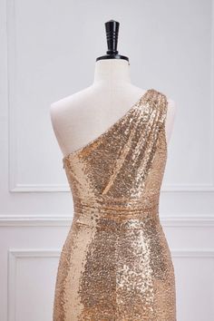 a gold sequin dress on a mannequin dummy with one shoulder draped over it