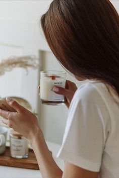 a woman is holding a candle and looking at her phone