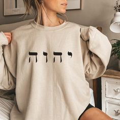 "✨Welcome to Faithful Deliveries!✨ 50% of all profits are donated to Kingdom-minded causes, so thank you for your support and business! ✨Product Details✨ Make a statement with this trendy Yahweh sweatshirt. This soft, comfy crewneck features the Hebrew letters י ה ו ה (pronounced Yahweh), notably known as the Name God gives Himself in Exodus 3. Used throughout the Bible, this Name means \"I am,\" as God is sufficiently self-sustaining, self-existing, and the Creator of all. ✨Material & Care✨ This product is the classic Gildan 18000 Unisex Heavy Blend™ Crewneck Sweatshirt. This soft, comfy sweatshirt features a ribbed-knit collar to retain shape after washing, a loose fit, a sewn-in label, and no itchy side seams. It is 50% cotton, 50% polyester, and has a medium-heavy fabric (8.0 oz/yd² (2 Yahweh Sweatshirt, Kingdom Minded, Exodus 3, Comfy Crewneck, Jesus Sweatshirts, Hebrew Letters, Christian Sweatshirt, Names Of God, Comfy Sweatshirt