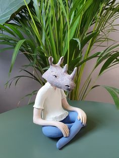 a ceramic animal sitting on top of a green table next to a potted plant