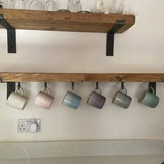 coffee mugs are hanging on the wall with wooden shelves