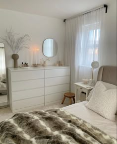 a bedroom with a bed, dresser and mirror on the wall next to it's windows