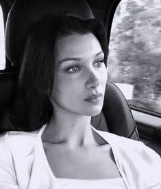 a woman sitting in the back seat of a car looking off into the distance with her eyes wide open